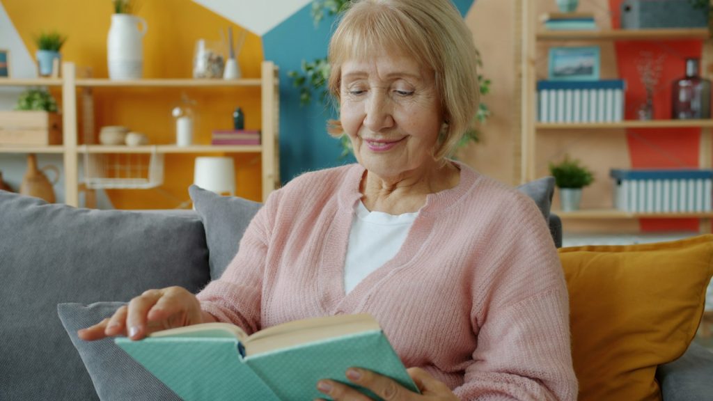 Elderly woman reading a book on a couch