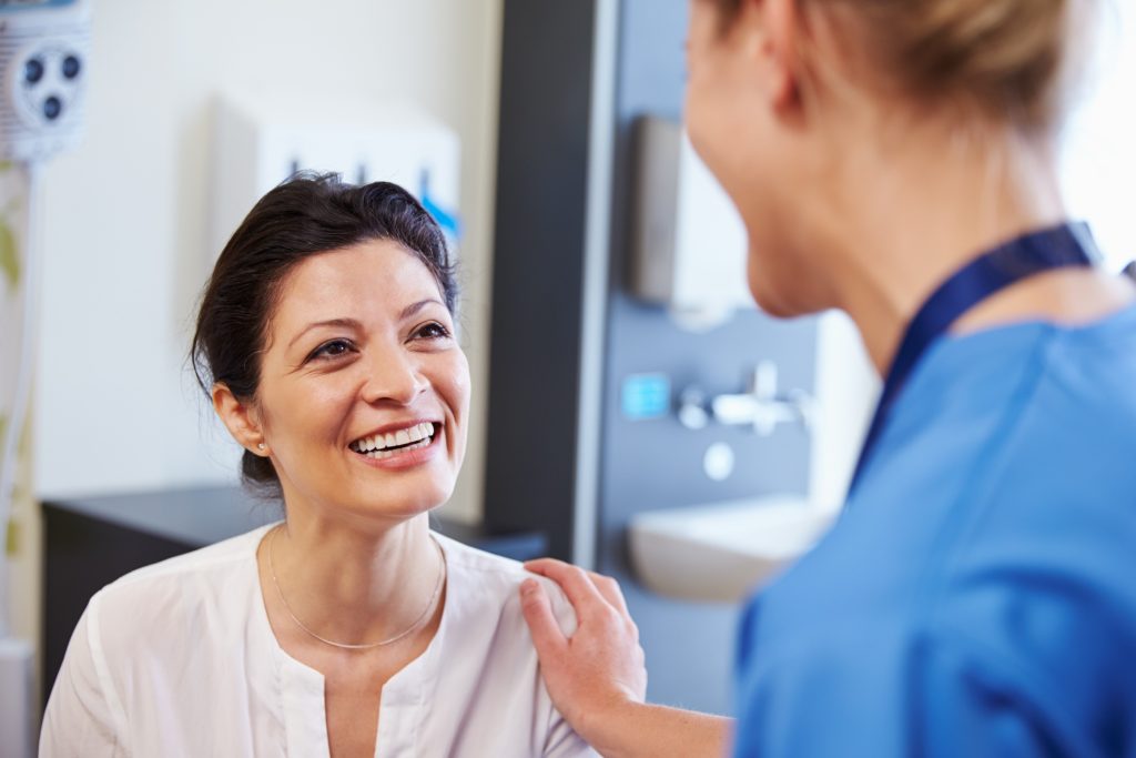 A smiling woman talking with a nurse